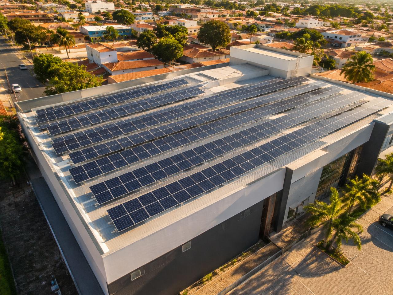 Vista aérea de prédio comercial com fileiras de painéis solares no telhado